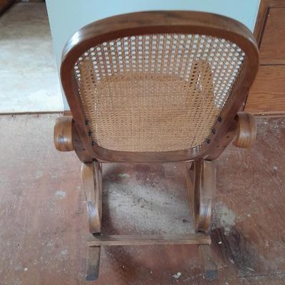 Wood framed wicker seat rocking chair with tall black lamp