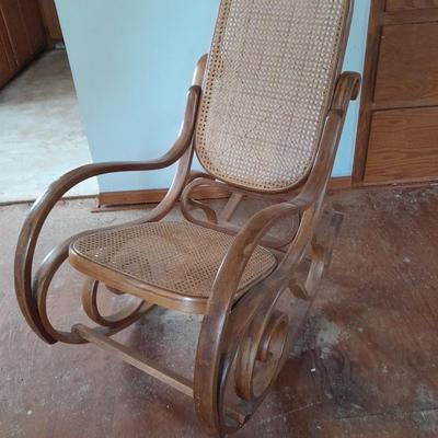 Wood framed wicker seat rocking chair with tall black lamp