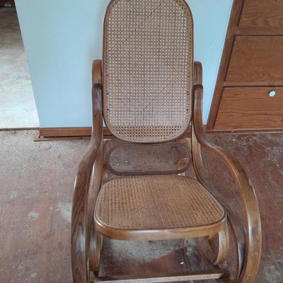 Wood framed wicker seat rocking chair with tall black lamp