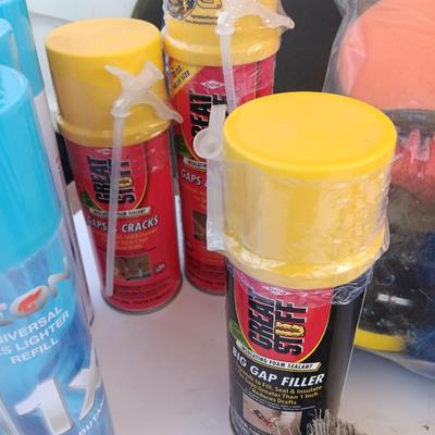 Assortment of household goods - bottles of butane - spray foam - a brush assortment and more