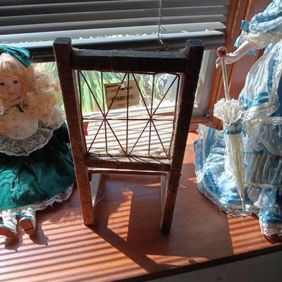 2 PRETTY PORCELAIN DOLLS AND A WOODEN DOLL CHAIR