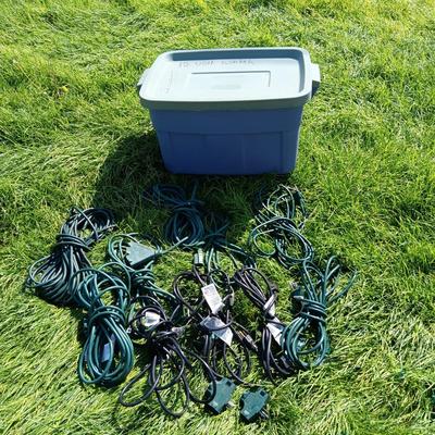 A VARIETY OF OUTDOOR EXTENSION CORDS AND A STORAGE TOTE