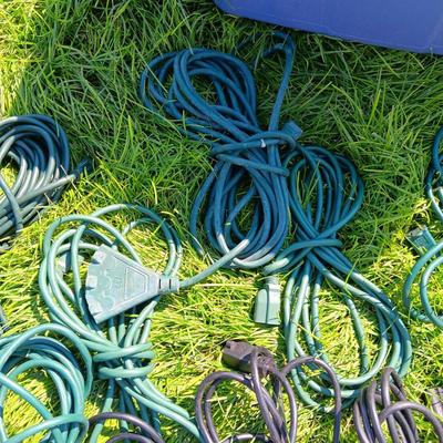 A VARIETY OF OUTDOOR EXTENSION CORDS AND A STORAGE TOTE