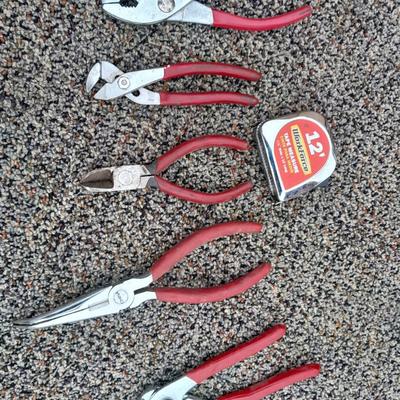 Red handled pliers and a tape measure