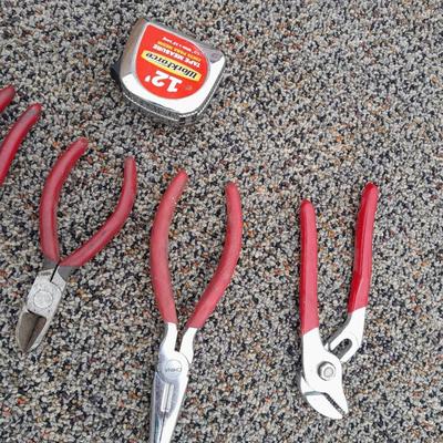 Red handled pliers and a tape measure