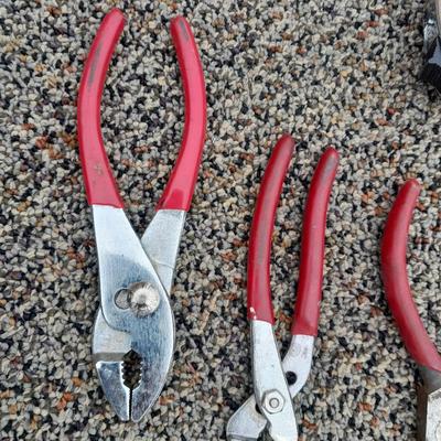 Red handled pliers and a tape measure
