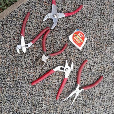 Red handled pliers and a tape measure