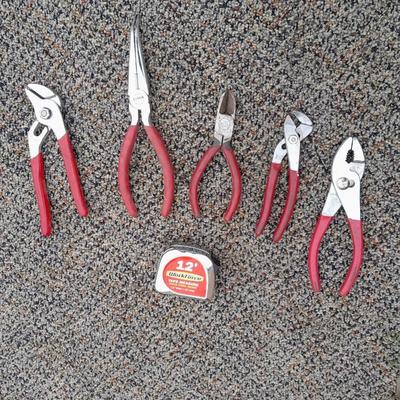 Red handled pliers and a tape measure