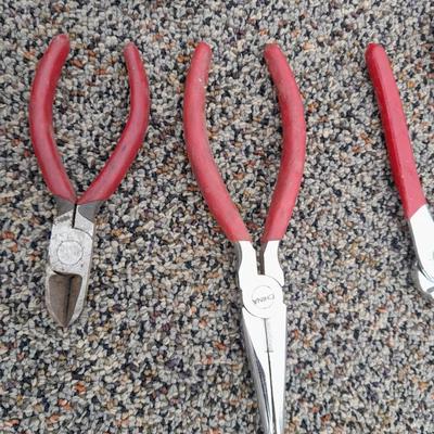 Red handled pliers and a tape measure