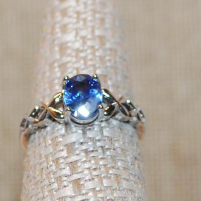 Size 7 Oval Blue 4 Prong Main Stone Ring with "Looped" Side Accents on a Silver Tone Band (2.2g)