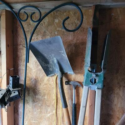 Posthole digger, flat shovel, hammer and outdoor plant stand