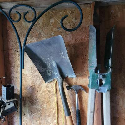 Posthole digger, flat shovel, hammer and outdoor plant stand