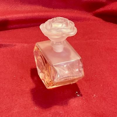 Pink perfume bottle with rose stopper and embossed flower on bottle