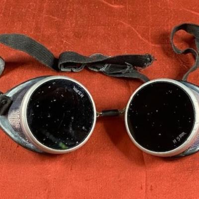 Sale Photo Thumbnail #18: This auction lot is for a pair of Antique Welding Goggles - Steam Punk Look. This is a pair of very old welders' glasses. the dark olive lenses are marked " WWSH or HSMM". The rubber has areas of white debris and the elastic traps have lost some spring bu