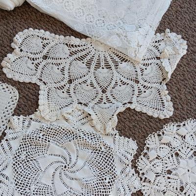 A LARGE AMOUNT OF LACEY MATERIAL AND HANDMADE DOILIES
