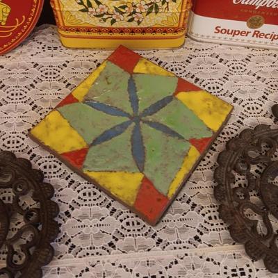 2 CAST IRON TRIVETS, CLAY HOT PLATE AND TINS