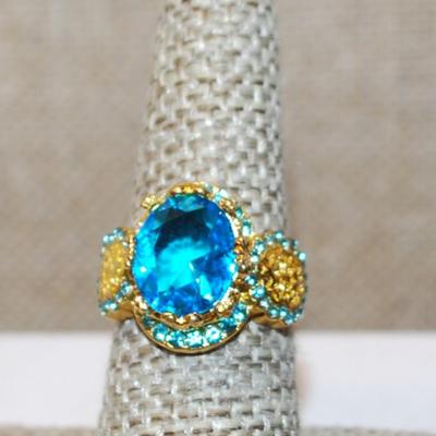 Size 7¼ Large Blue Transparent Stone Ring with Blue Side Accents on a Gold Tone Band (5.4g)