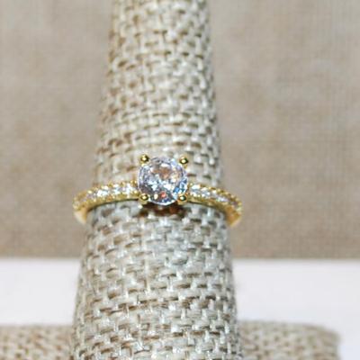 Size 7 Round Clear Main Stone Ring with Side Row Accents on a Gold Tone Band (1.9g)