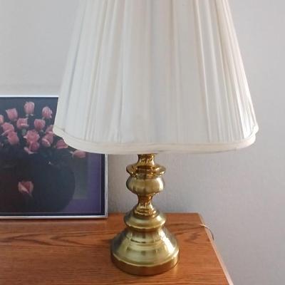 Brass colored table lamp with framed artwork of pink roses