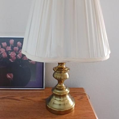 Brass colored table lamp with framed artwork of pink roses