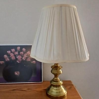 Brass colored table lamp with framed artwork of pink roses