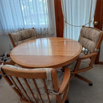 Beautiful drop leaf Oak pedestal table with three upholstered chairs on casters