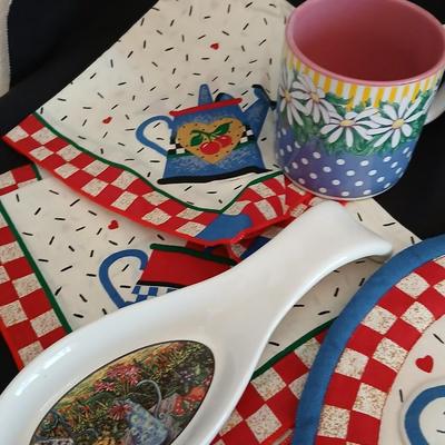 Two Garden Bloom placemats with fabric handmade apples in a basket, and mugs with a spoon rest