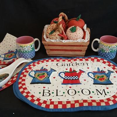 Two Garden Bloom placemats with fabric handmade apples in a basket, and mugs with a spoon rest