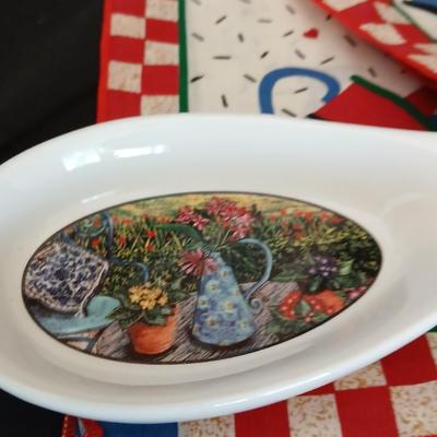 Two Garden Bloom placemats with fabric handmade apples in a basket, and mugs with a spoon rest