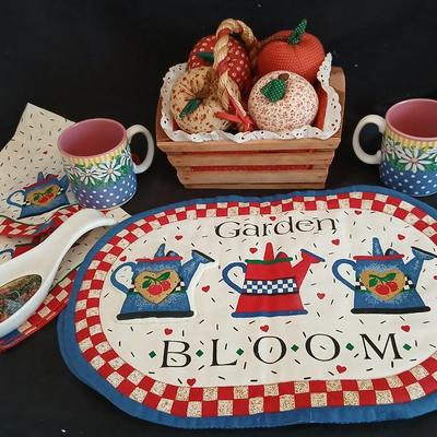 Two Garden Bloom placemats with fabric handmade apples in a basket, and mugs with a spoon rest