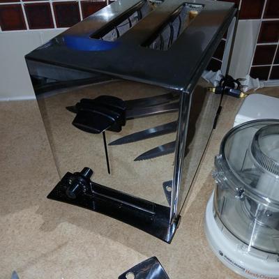 Chrome colored toaster with small electric chopper and wood handled knives
