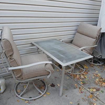 Two patio chairs and cushions with small glass topped patio table
