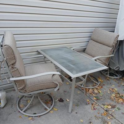 Two patio chairs and cushions with small glass topped patio table