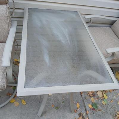 Two patio chairs and cushions with small glass topped patio table