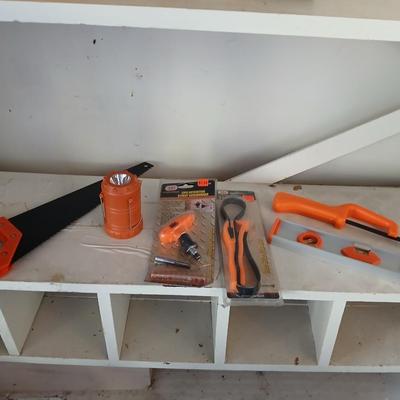 Grouping of orange tools, saws, level, strap wrench, flashlight, and more