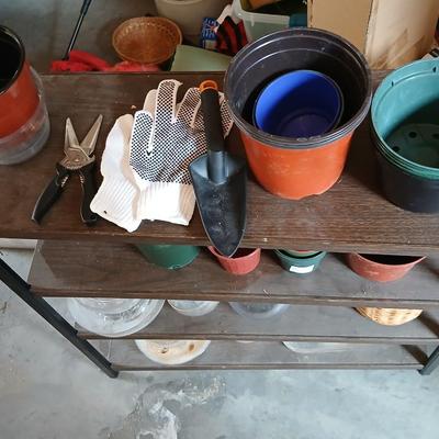 Lots of flowerpots and vases with a small metal shelf
