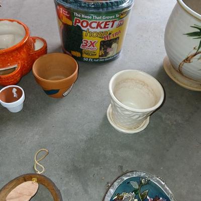 Ceramic plant pots and whirl gig yard art with a new pocket hose