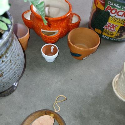 Ceramic plant pots and whirl gig yard art with a new pocket hose