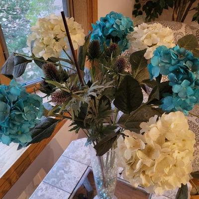 Sale Photo Thumbnail #181: Blue and cream hydrangea flowers with greenery, in glass vase with colored glass rocks.