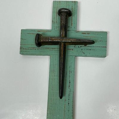 Painted wood cross with large nails or spikes.