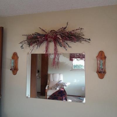 Large mirror with a pair of wooden candle sconces and a dried sash