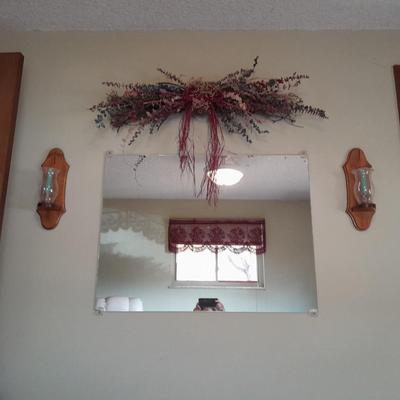 Large mirror with a pair of wooden candle sconces and a dried sash