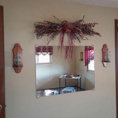 Large mirror with a pair of wooden candle sconces and a dried sash
