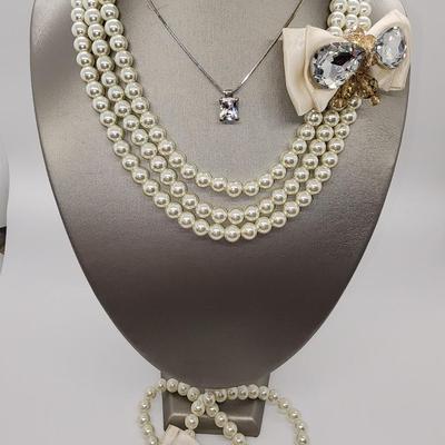 LOT 96:: Triple Strand Faux Glass Pearls with Accent Bow, Matching Bracelet and a Goldtone CZ Pendant Necklace by Express