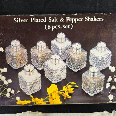 Sale Photo Thumbnail #483: This auction lot is for a Boxed Set of Individual Salt & Pepper Shakers. This boxed set includes 8 pairs of silver-plated caps with glass salt and pepper shakers.  The box is a tad tattered but the shakers have never been used.  Perfect for your next dinn