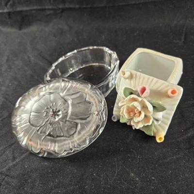 Sale Photo Thumbnail #518: This auction lot is for a Small Trinket Box Duo.  This lot is for 2 small trinket boxes.  One is china with raised flowers on top of lid.  It measures about 2-inches square.  The other has a Lalique-style satin floral lid with glass bottom.  It is an oval