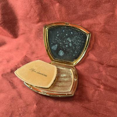 Sale Photo Thumbnail #551: This auction lot is for a Vintage Purse Shaped Elgin America Compact. This compact is made by Elgin America.  The cover has a tri-finish design of shinny brass, satin and rose gold brass.  It contains no powder.  The mirror shows fogging due to age.  It m