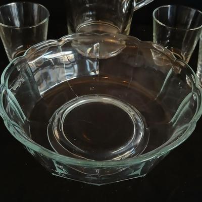 Glass water pitcher with six small juice glasses and a snack bowl with a platter