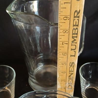 Glass water pitcher with six small juice glasses and a snack bowl with a platter