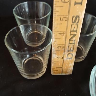 Glass water pitcher with six small juice glasses and a snack bowl with a platter